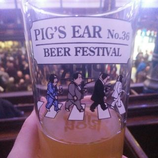 A photo of Pig’s Ear Beer Festival’s 2019 pint glass, with a crowd of people in the background